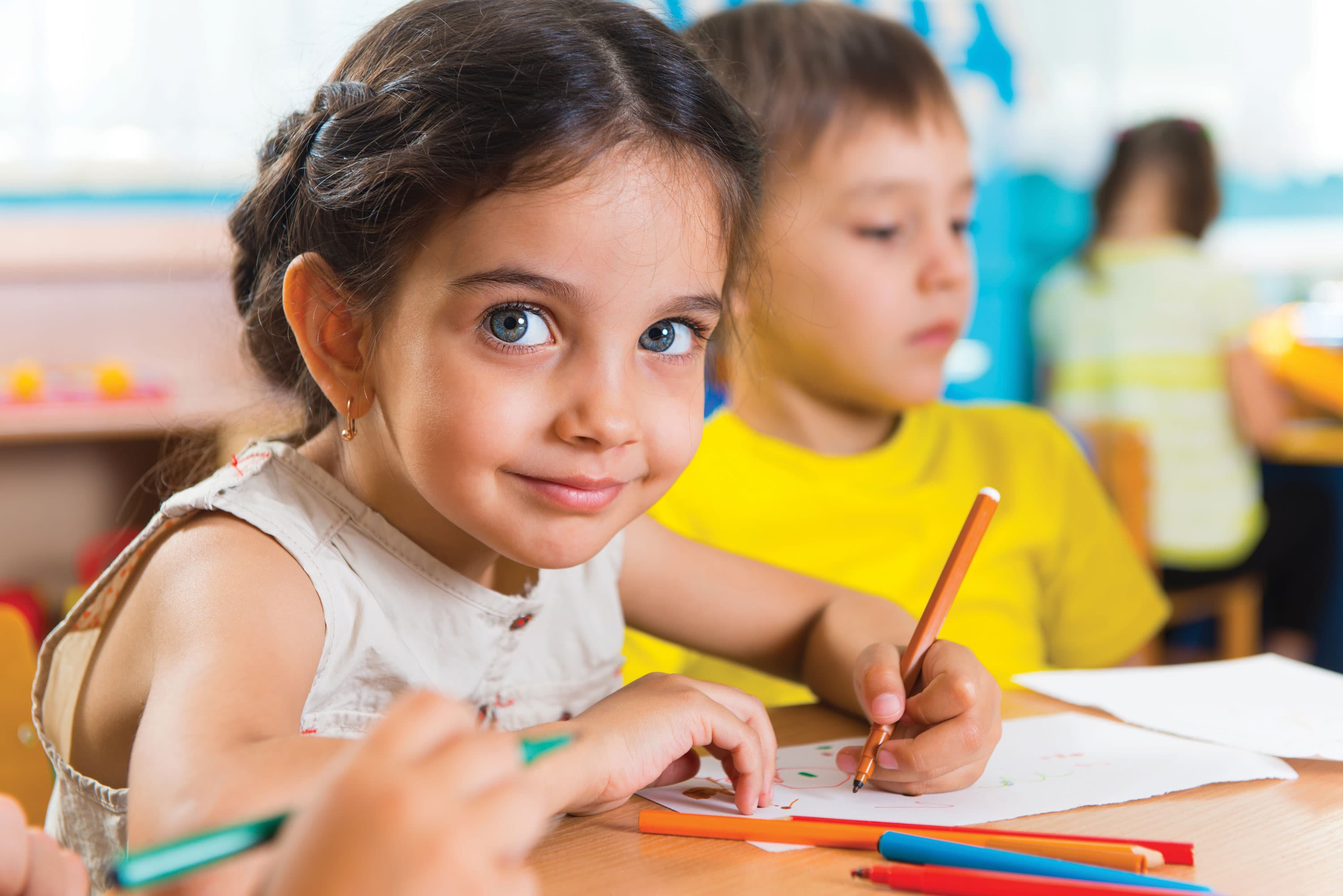 Young children coloring at a table in a classroom