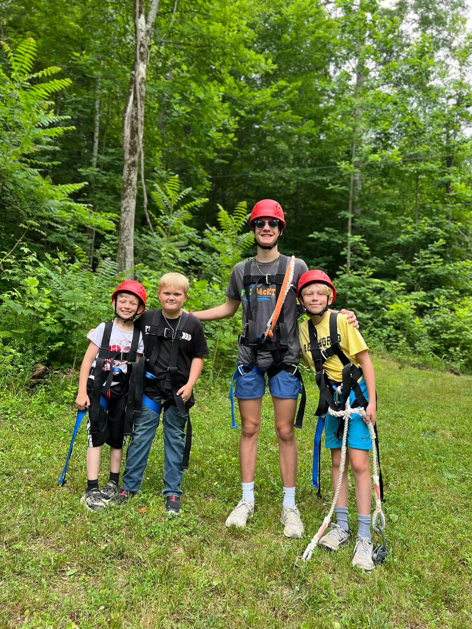 Kids in helmets and climbing harnesses with a counselor