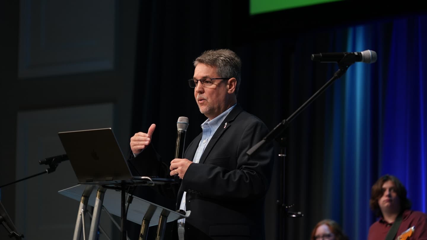 Speaker teaching from a laptop at a microphone