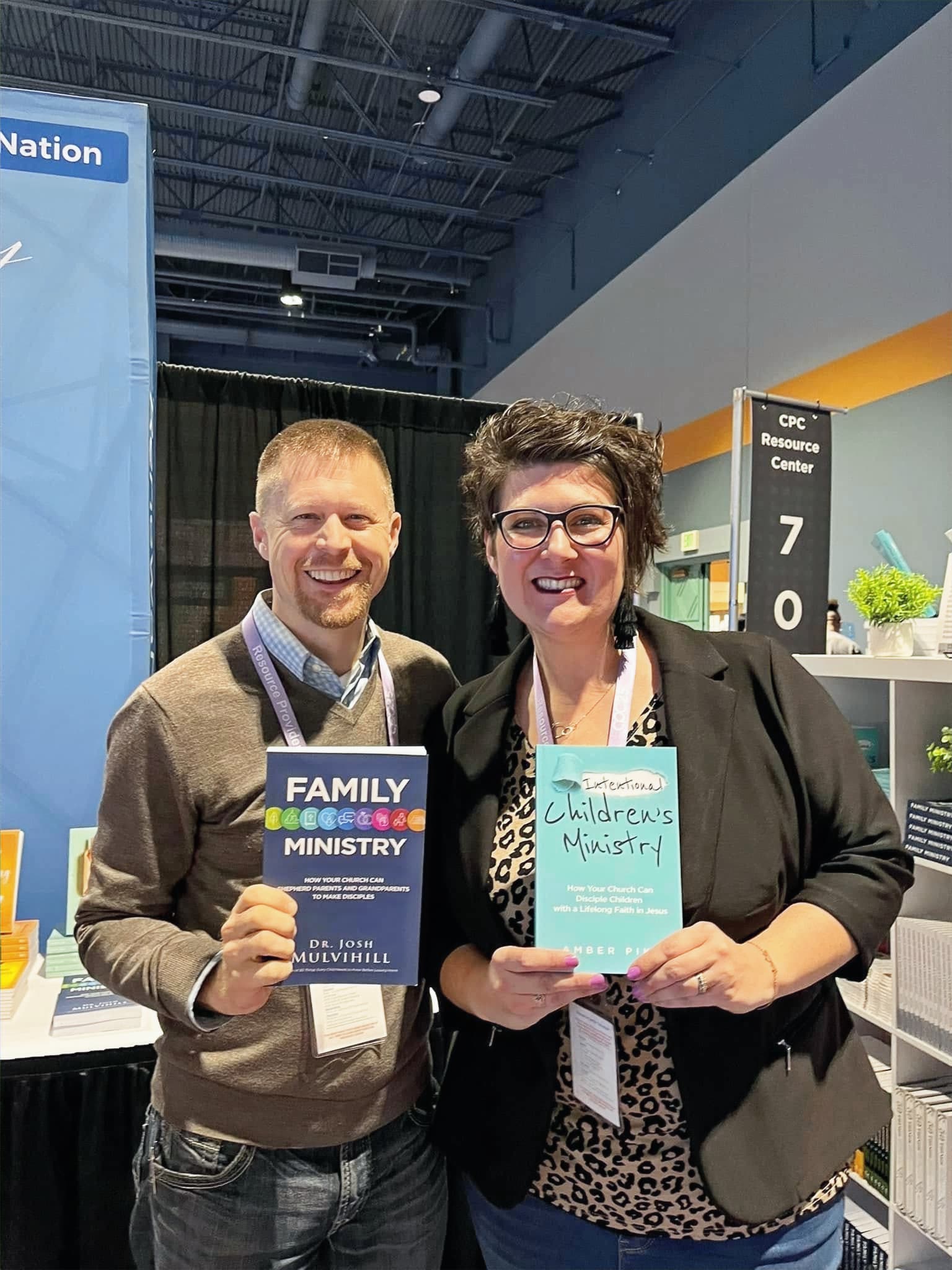 Couple holding Family Ministry and Children's Ministry books at a booth