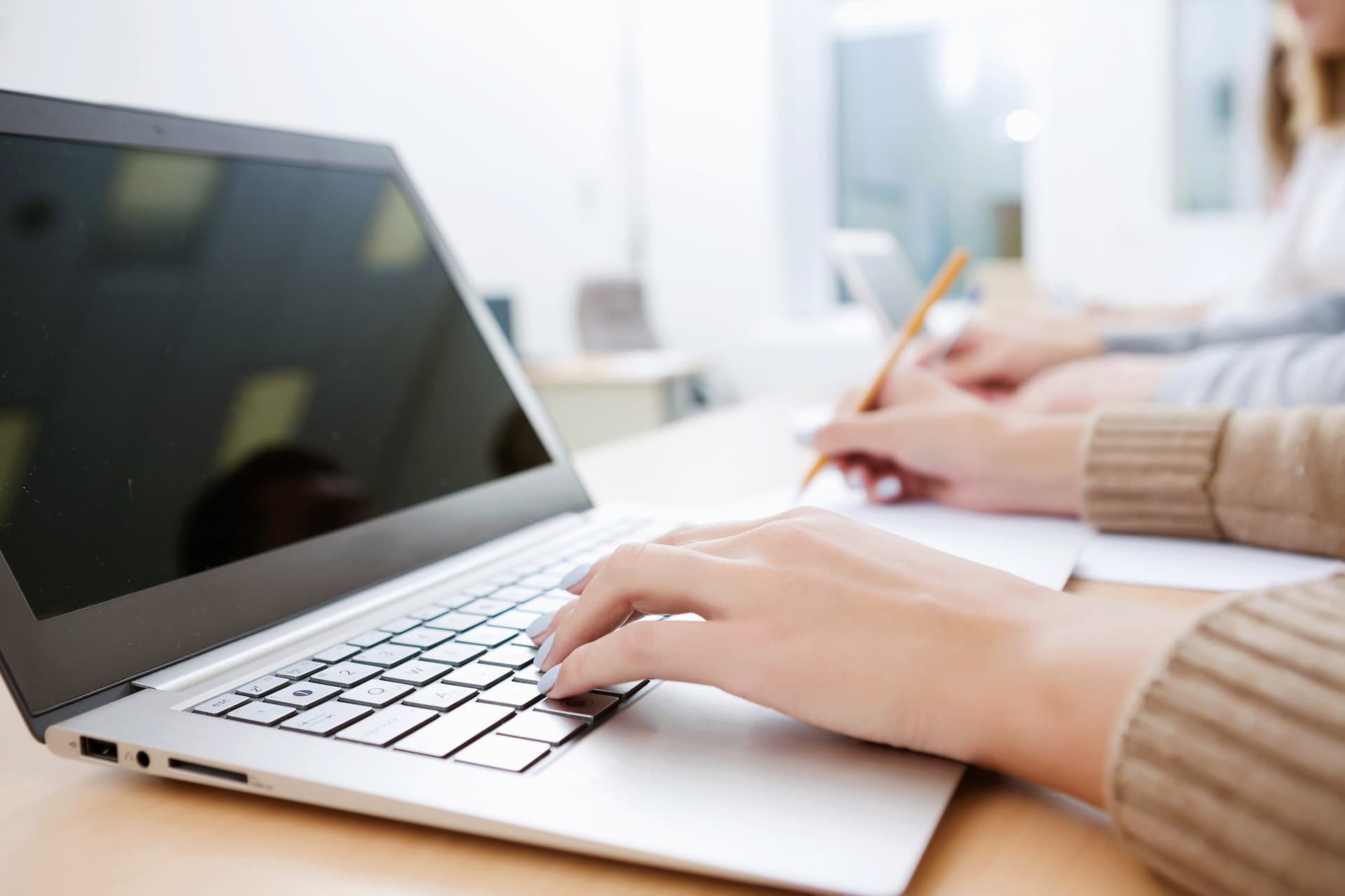 Hands taking notes beside an open laptop while planning next steps
