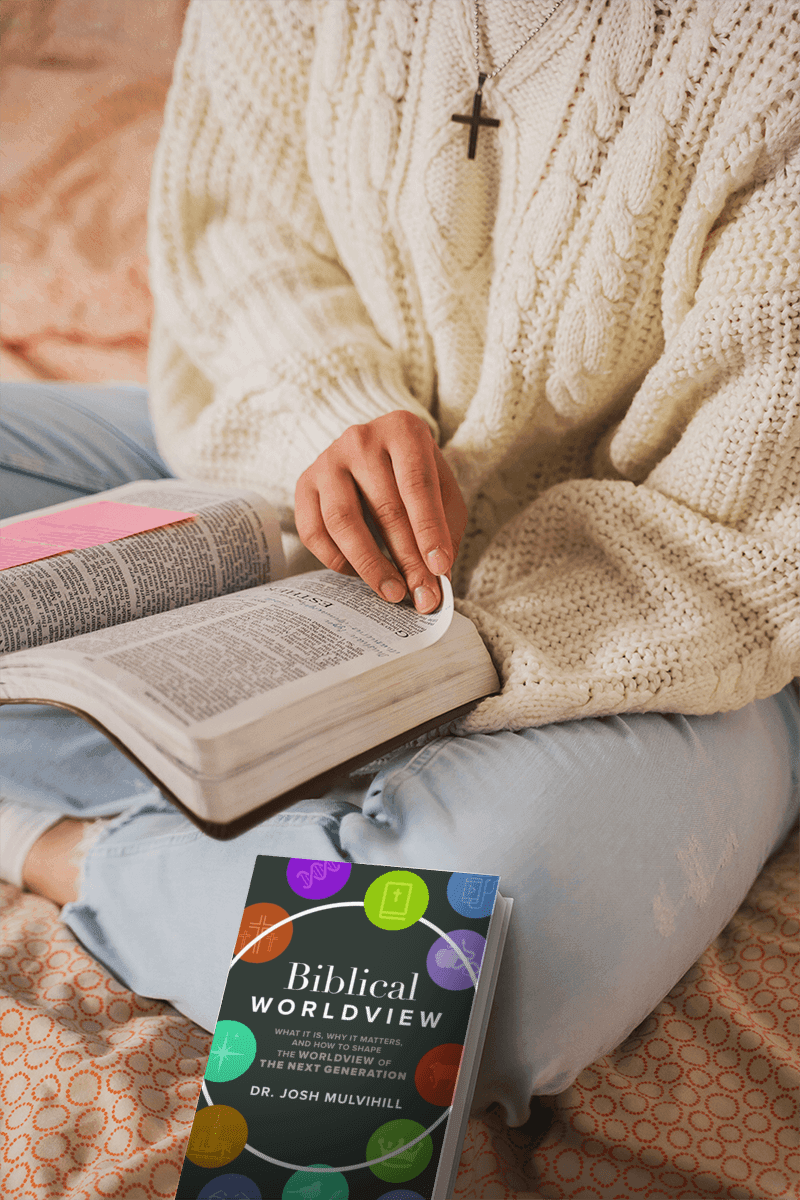 Person reading the Bible with the Biblical Worldview book nearby
