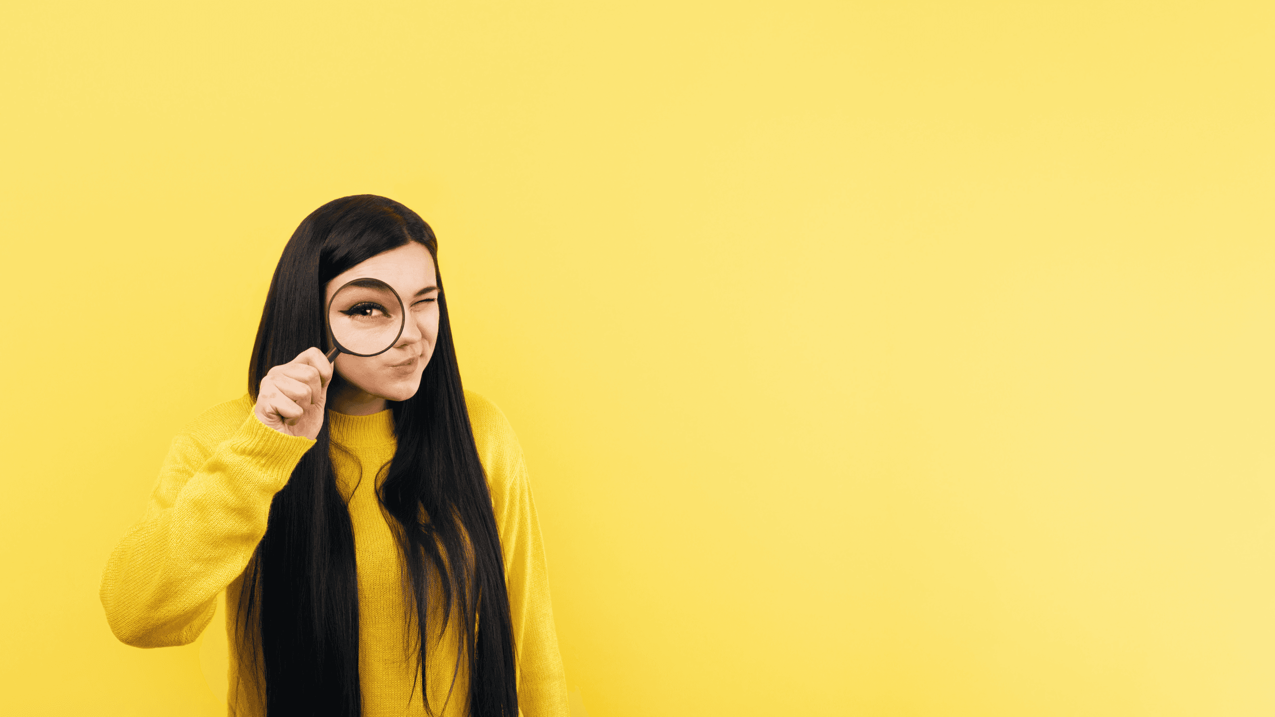 Woman looking through a magnifying glass on a yellow background