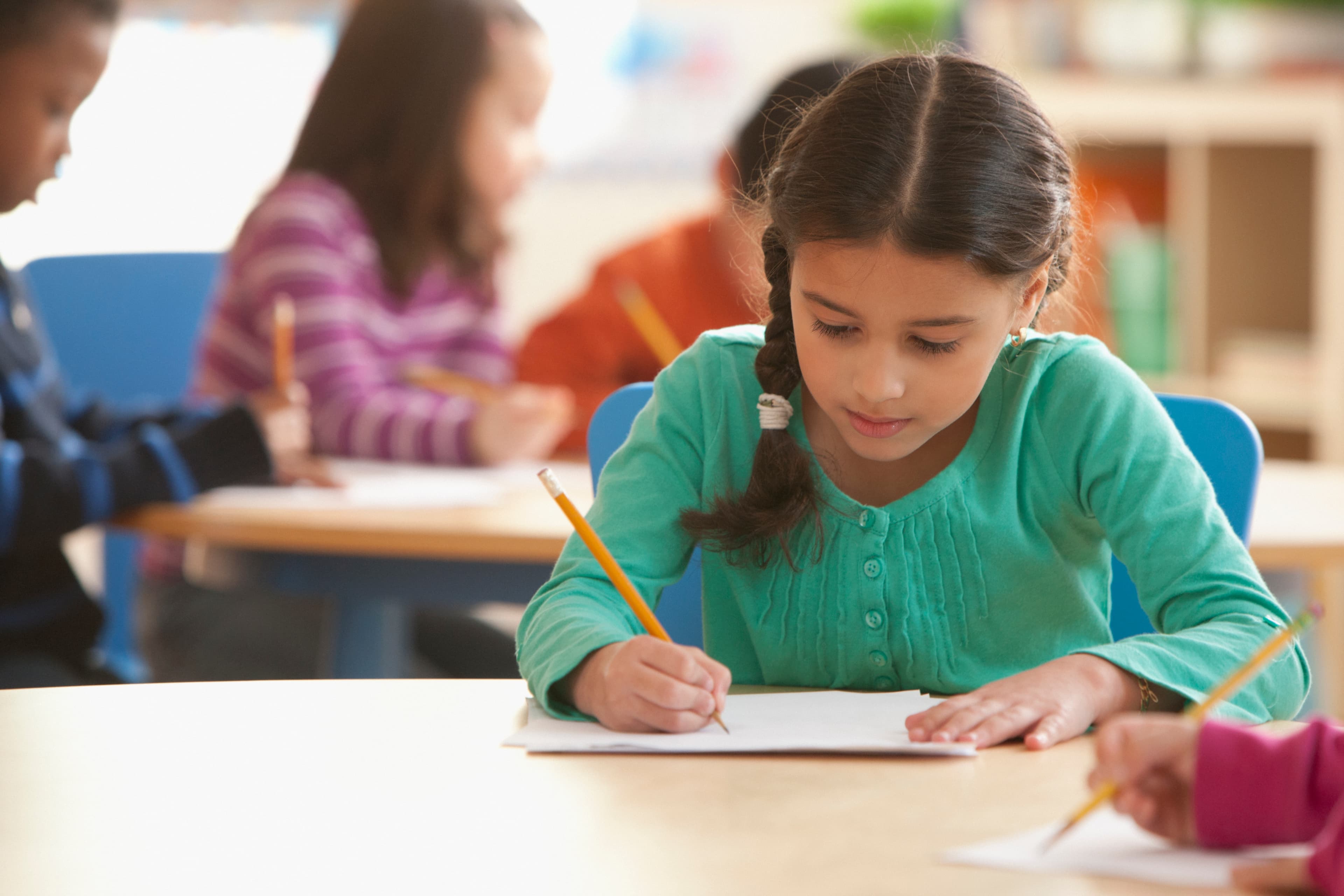 Girl raising her hand in a bright classroom